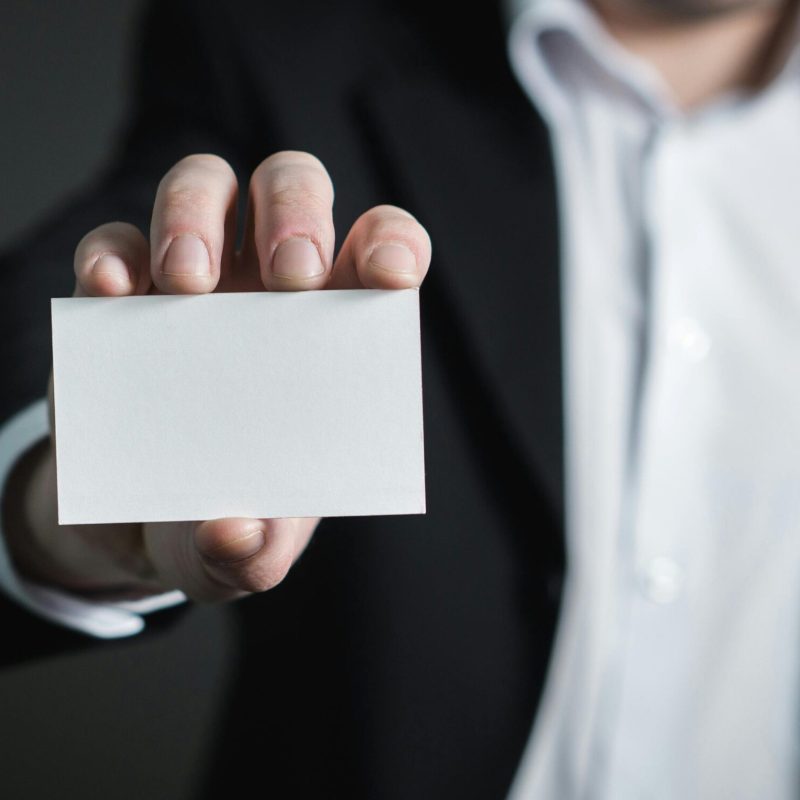 A man in a suit presenting a blank business card for corporate usage.