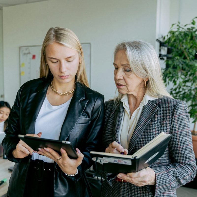 Professional women discussing work in a modern office setting with colleagues.